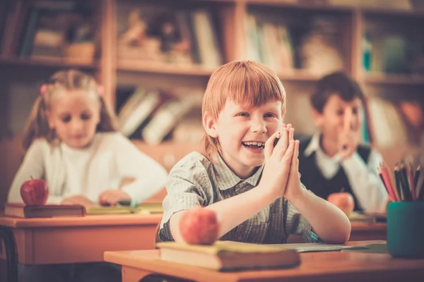 Mały rudy uczniak za biurkiem szkoły podczas lekcji — Zdjęcie stockowe