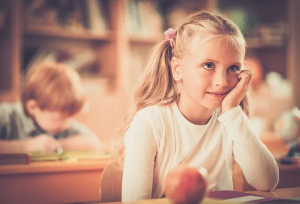Malá školačka, sedí za stolem školy během lekce ve škole — Stock fotografie