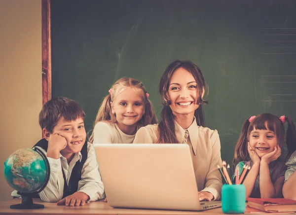 Groep van gelukkig klasgenoten met hun leraar in de klas in de buurt van blackboard — Stockfoto