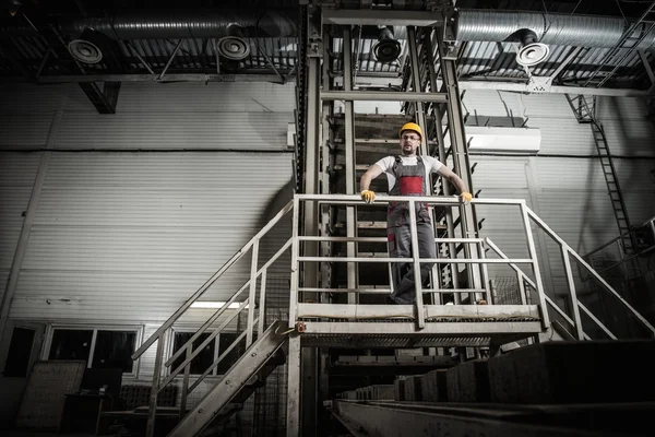 Un hombre con un sombrero de seguridad en una fábrica —  Fotos de Stock