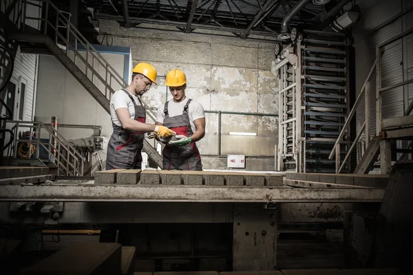 在一家工厂工人和工头在安全帽执行质量检查 — 图库照片