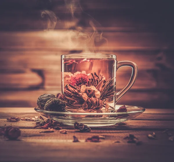 Glass cup with tea flower against wooden background — Stock Photo, Image