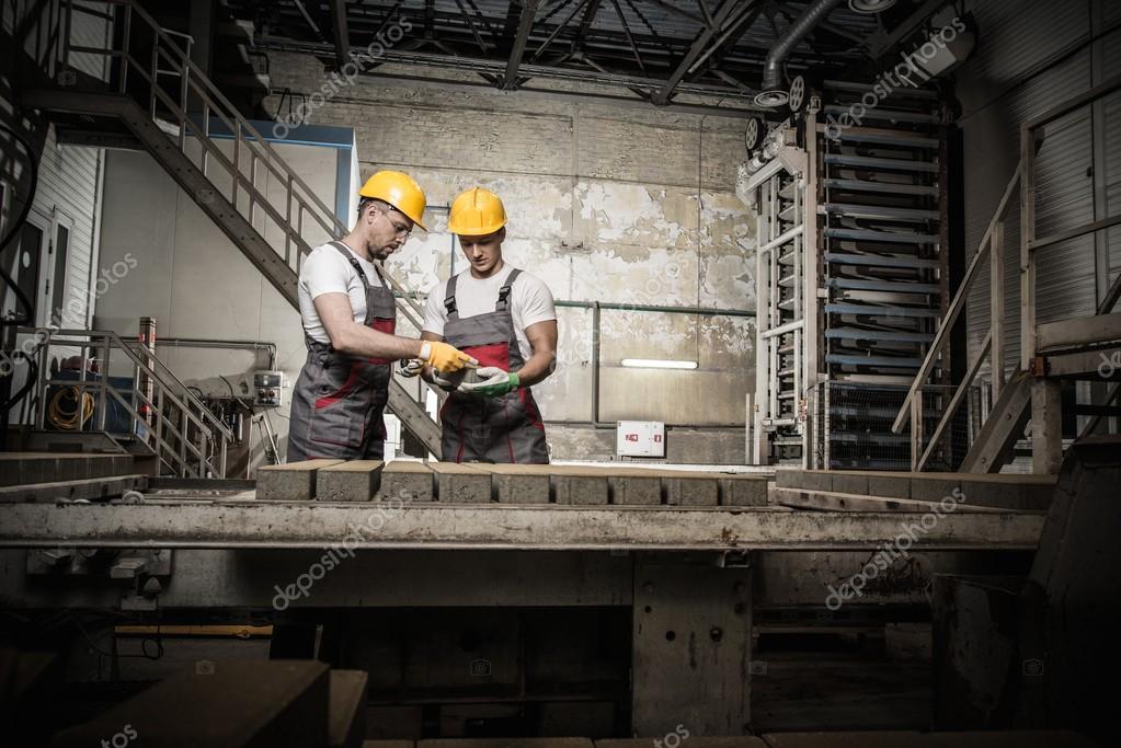 Worker and foreman in a safety hats performing quality check on a