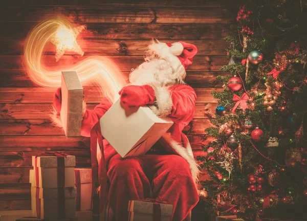 Weihnachtsmann im hölzernen Heim-Interieur mit Geschenkbox, aus der ein magischer Stern fliegt — Stockfoto