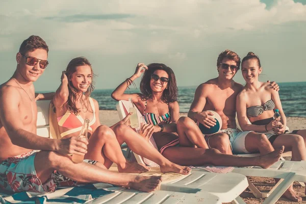 Grupo de amigos multiétnicos con bebidas relajantes en una playa —  Fotos de Stock