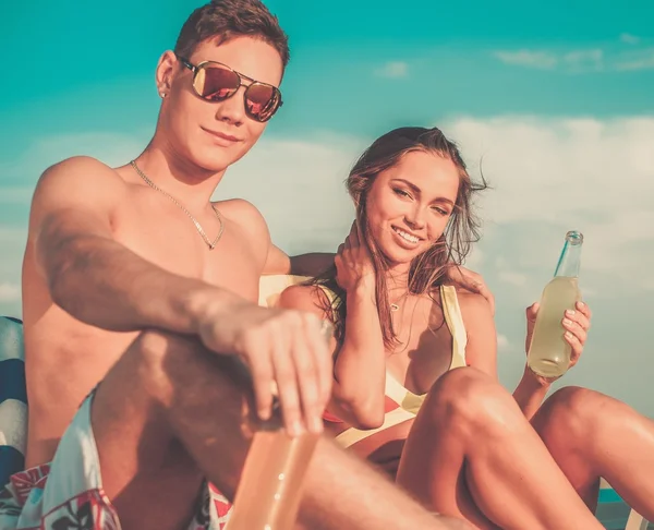 Young couple relaxing on a deck chairs on a beach — Stock Photo, Image