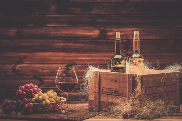 Garrafas de vinho tinto e branco, vidro e uva em um interior de madeira — Fotografia de Stock