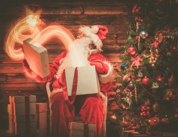 拿着礼物盒与魔法星飞离它的木制居家室内圣诞老人 — 图库照片