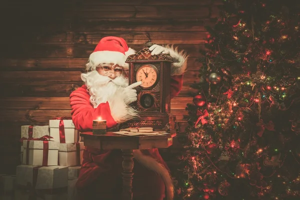 Santa Claus in wooden home interior showing time on a clock — Stock Photo, Image