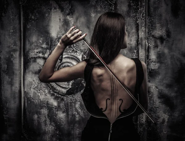 Femme en robe avec violon corps art tenant arc — Photo