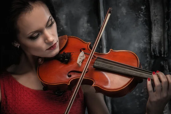 Jovem de vestido vermelho tocando violino no interior místico — Fotografia de Stock