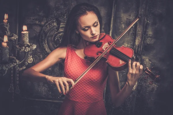 Mujer joven en vestido rojo tocando el violín en el interior místico —  Fotos de Stock