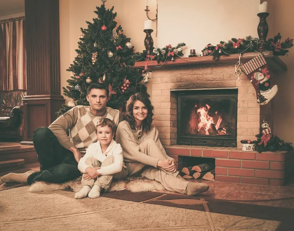 Família perto de lareira no interior da casa decorada de Natal — Fotografia de Stock