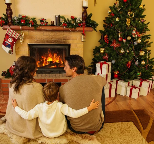 Familia cerca de la chimenea en Navidad decorado interior de la casa con caja de regalo —  Fotos de Stock