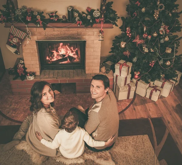 Família perto de lareira no interior da casa decorada de Natal com caixa de presente — Fotografia de Stock