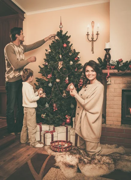 Famiglia vicino al camino in casa decorata di Natale interno con scatola regalo — Foto Stock