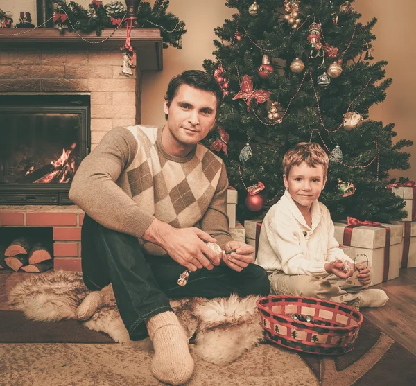 Família perto de lareira no interior da casa decorada de Natal com caixa de presente — Fotografia de Stock