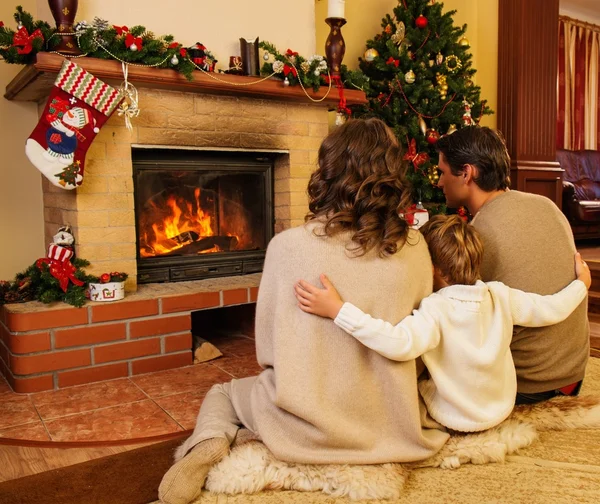 Familia cerca de la chimenea en Navidad decorado interior de la casa con caja de regalo — Foto de Stock