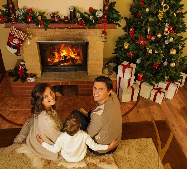 Família perto de lareira no interior da casa decorada de Natal com caixa de presente — Fotografia de Stock