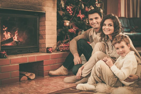 Familie am Kamin im weihnachtlich dekorierten Haus Innenausstattung mit Geschenkbox — Stockfoto