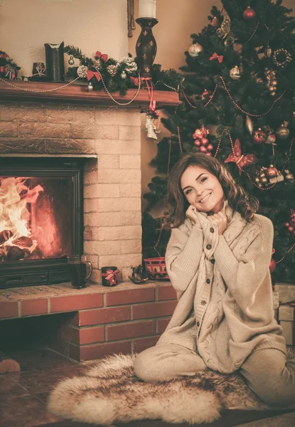 Junge Frau am Kamin in weihnachtlich dekoriertem Haus — Stockfoto