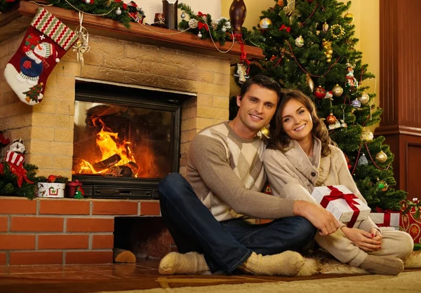 Cuplu în apropierea șemineului în interiorul casei decorate de Crăciun — Fotografie, imagine de stoc