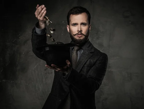 Handsome well-dressed man in jacket with hat full of coins — Stock Photo, Image