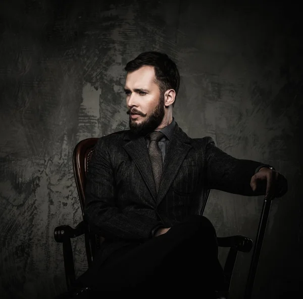 Handsome well-dressed man with walking stick sitting in leather chair — Stock Photo, Image