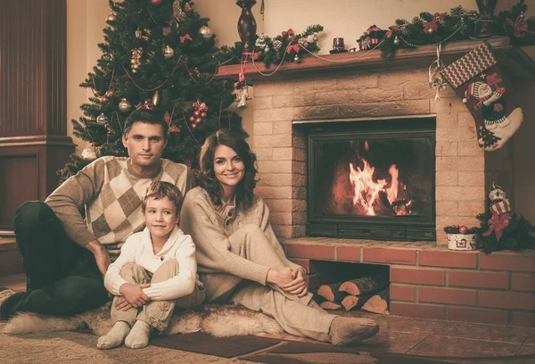 Family near fireplace in Christmas decorated house interior — Stock Photo, Image