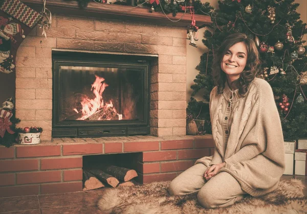 Mujer joven cerca de la chimenea en el interior de la casa decorada de Navidad — Foto de Stock