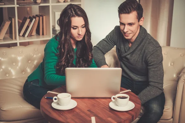 Ungt par med laptop och kaffe efter bord — Stockfoto