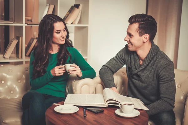 Couple with coffee and book discussing something in cafe — Stock Photo, Image