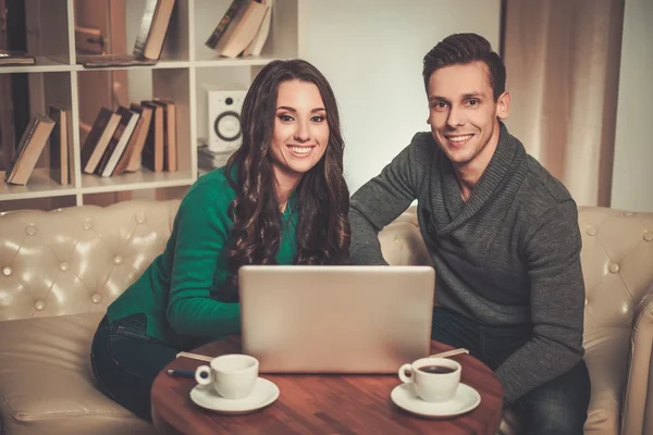 Jovem casal com laptop e café atrás da mesa — Fotografia de Stock