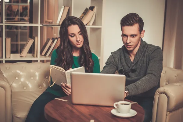 Pareja joven con portátil y café detrás de la mesa —  Fotos de Stock