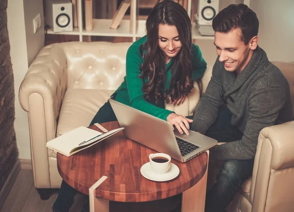 Jovem casal com laptop e café atrás da mesa — Fotografia de Stock