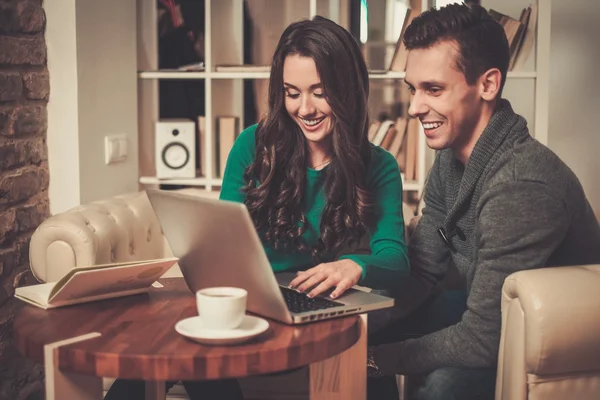 Jong (echt) paar met laptop en koffie achter tafel — Stockfoto