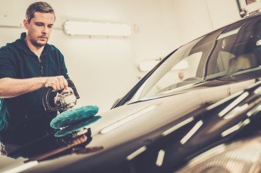 Man on a car wash polishing car with a polish machine  clipart