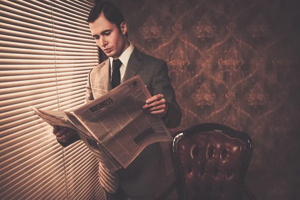 Mann im Anzug liest Zeitung am Fenster — Stockfoto