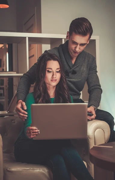 Jovem casal com laptop atrás da mesa — Fotografia de Stock