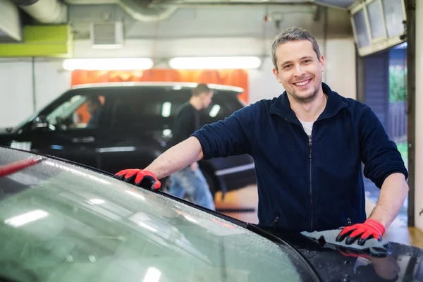 Vrolijke werknemer afvegen auto op een auto wassen — Stockfoto