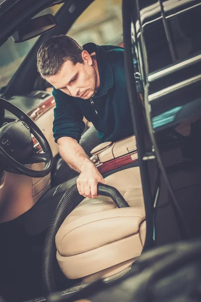 Werknemer op een auto wassen auto-interieur met stofzuiger schoonmaken — Stockfoto