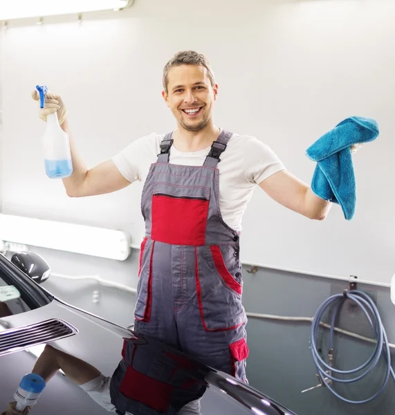 Trabajador feliz en un lavado de coches con un spray — Foto de Stock