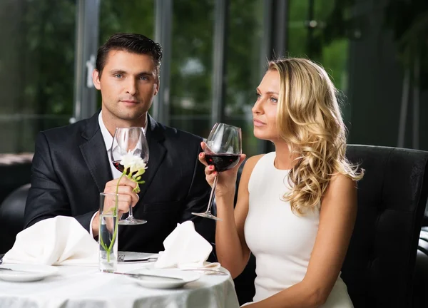 Casal alegre em um restaurante com copos de vinho tinto — Fotografia de Stock