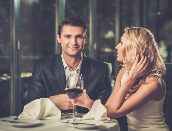 Fröhliches Paar in einem Restaurant mit einem Glas Rotwein — Stockfoto