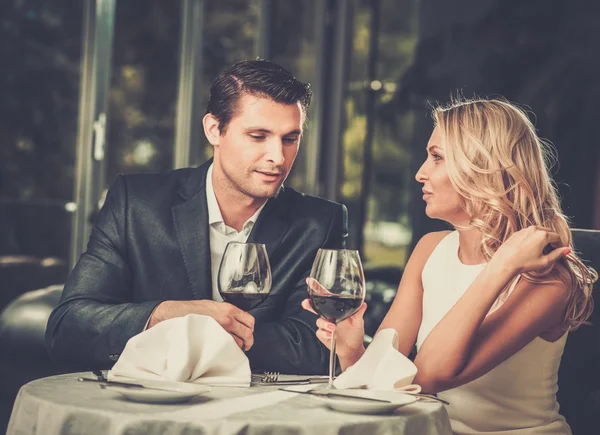 Casal alegre em um restaurante com copos de vinho tinto — Fotografia de Stock