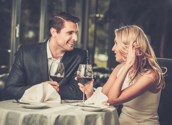 Pareja alegre en un restaurante con copas de vino tinto — Foto de Stock