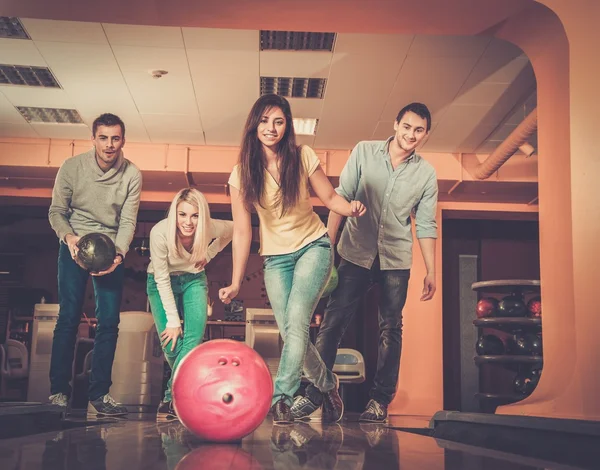 Grupo de cuatro jóvenes sonriendo jugando a los bolos — Foto de Stock