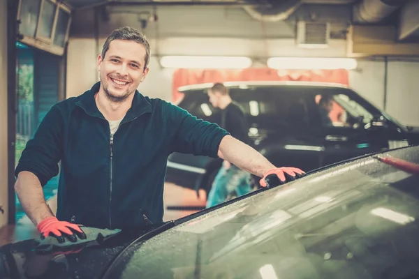 Cheerful worker wiping car on a car wash — Stock Photo, Image
