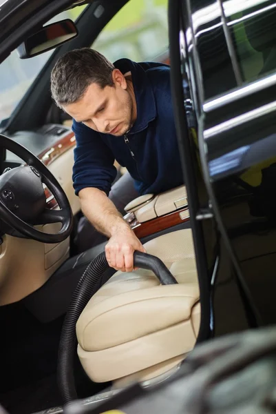 Arbeiter in einer Autowaschanlage, die den Innenraum mit Staubsauger reinigt — Stockfoto