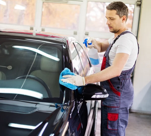 Arbeiter in einer Waschanlage reinigt Auto mit Spray — Stockfoto